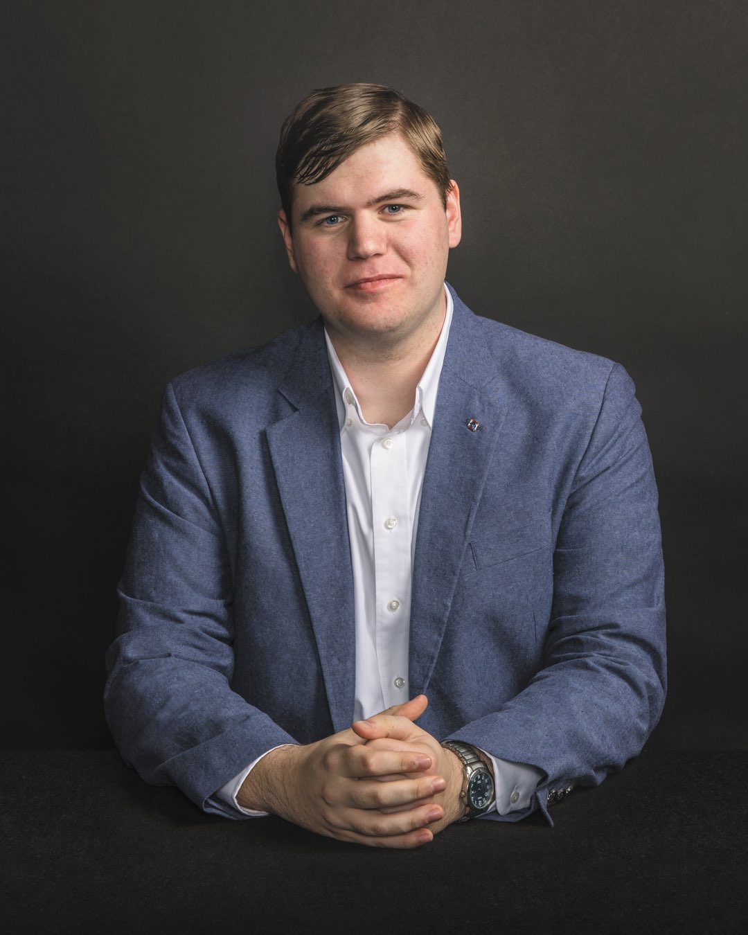 Rising junior Keith Mathews with hands folded in a blue linen suit jacket and white dress shirt