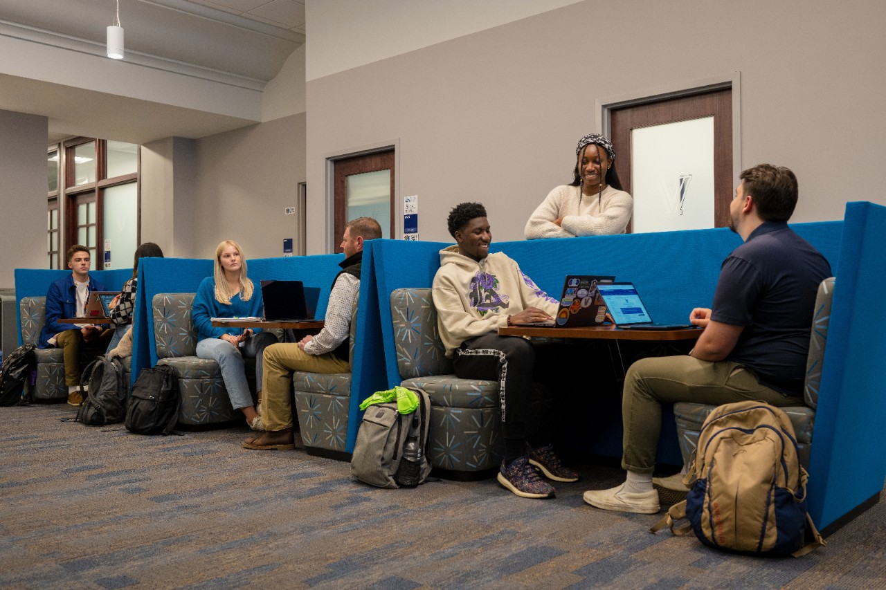 Several students and career center employees sitting at tables in the career center talking.