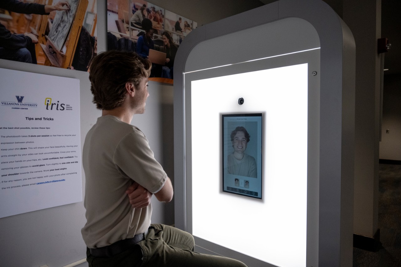 Student looking at a screen with an image of their headshot displayed on it.