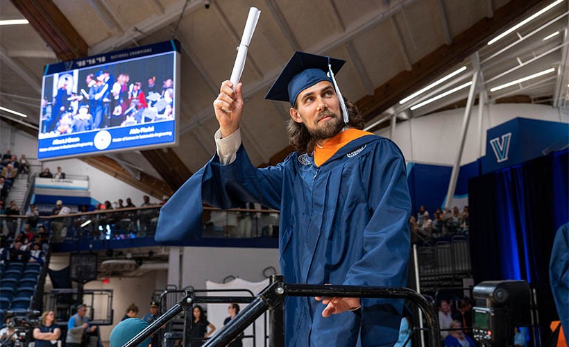 A male graduate holding a diploma