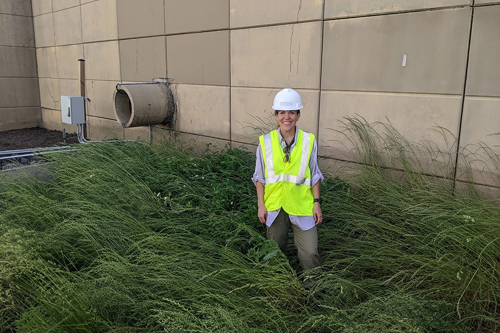 Virginia Smith, PhD, standing in tall grassy area near a concrete wall
