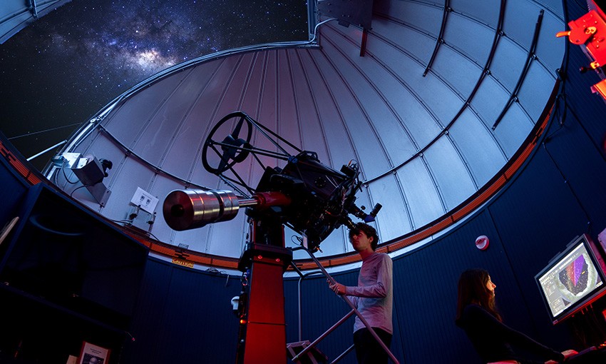 Student observes the night sky through a telescope.