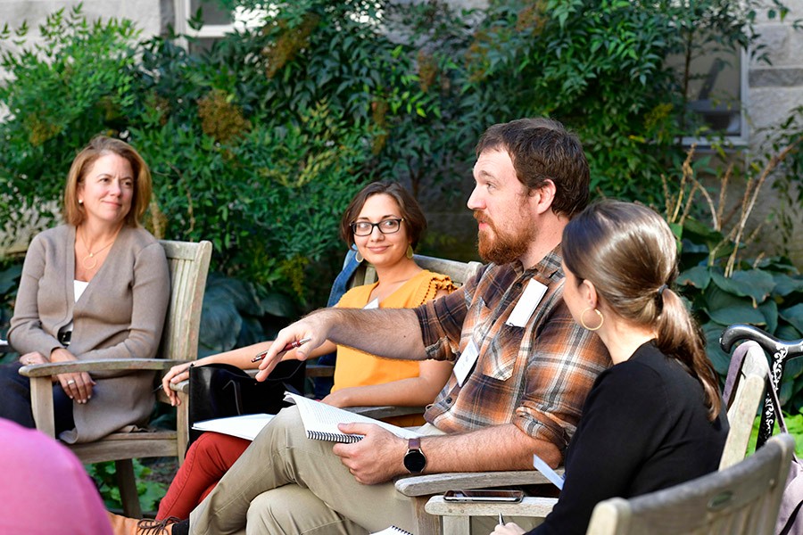 Humanities alumi and faculty sitting outside talking.