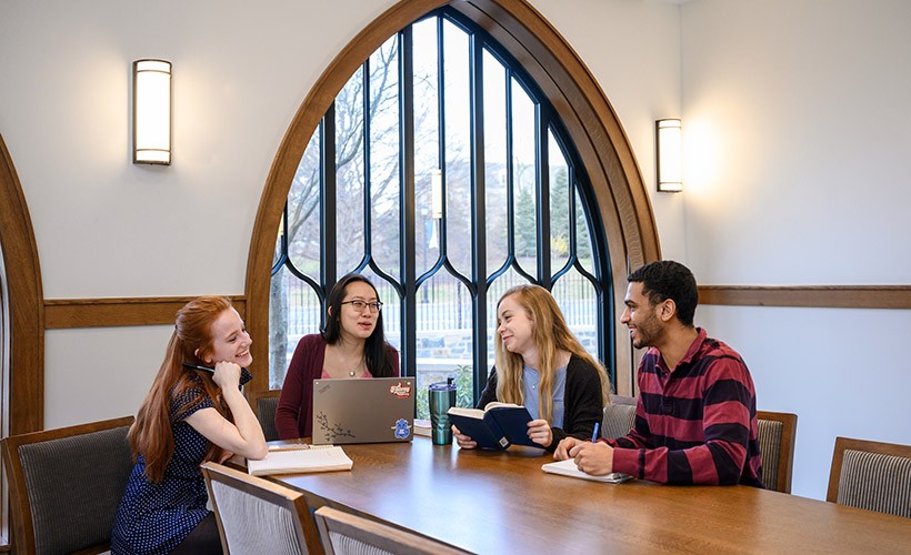Students sit around a table in a discussion
