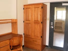 View of desk, wardrobe and full-length mirror on the back of the door of a Sheehan Hall double room.