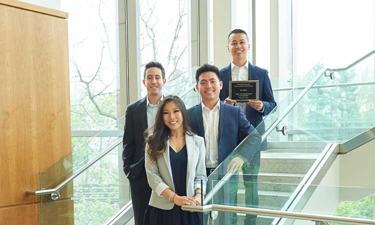 Students standing on steps with a plaque