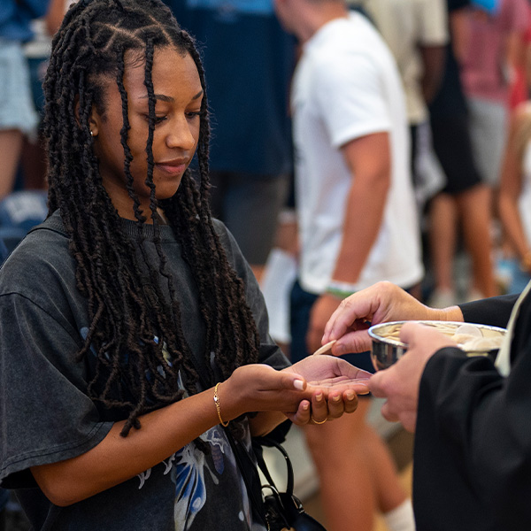 A young woman receives Communion in her hands.