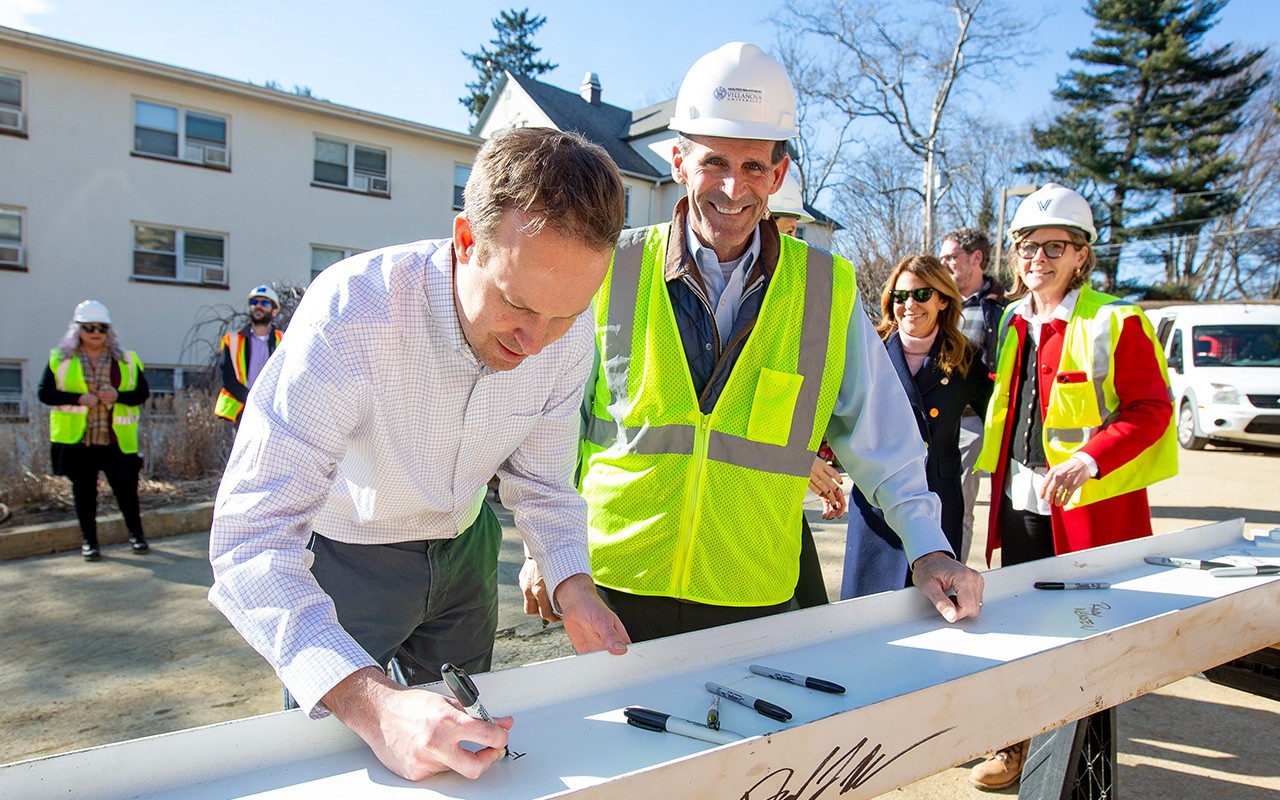 Bob Morro wearing a white hard hat and neon safety vest smiles directly at the camera during the topping off ceremony for Drosdick Hall.