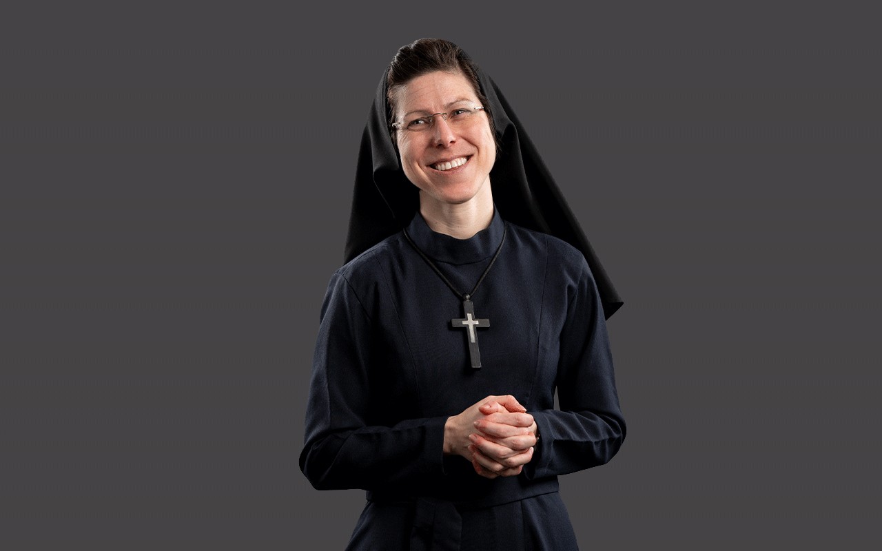 Sister Brigid Mary Meeks, RSM, in a standing pose with her hands clasped wearing her habit